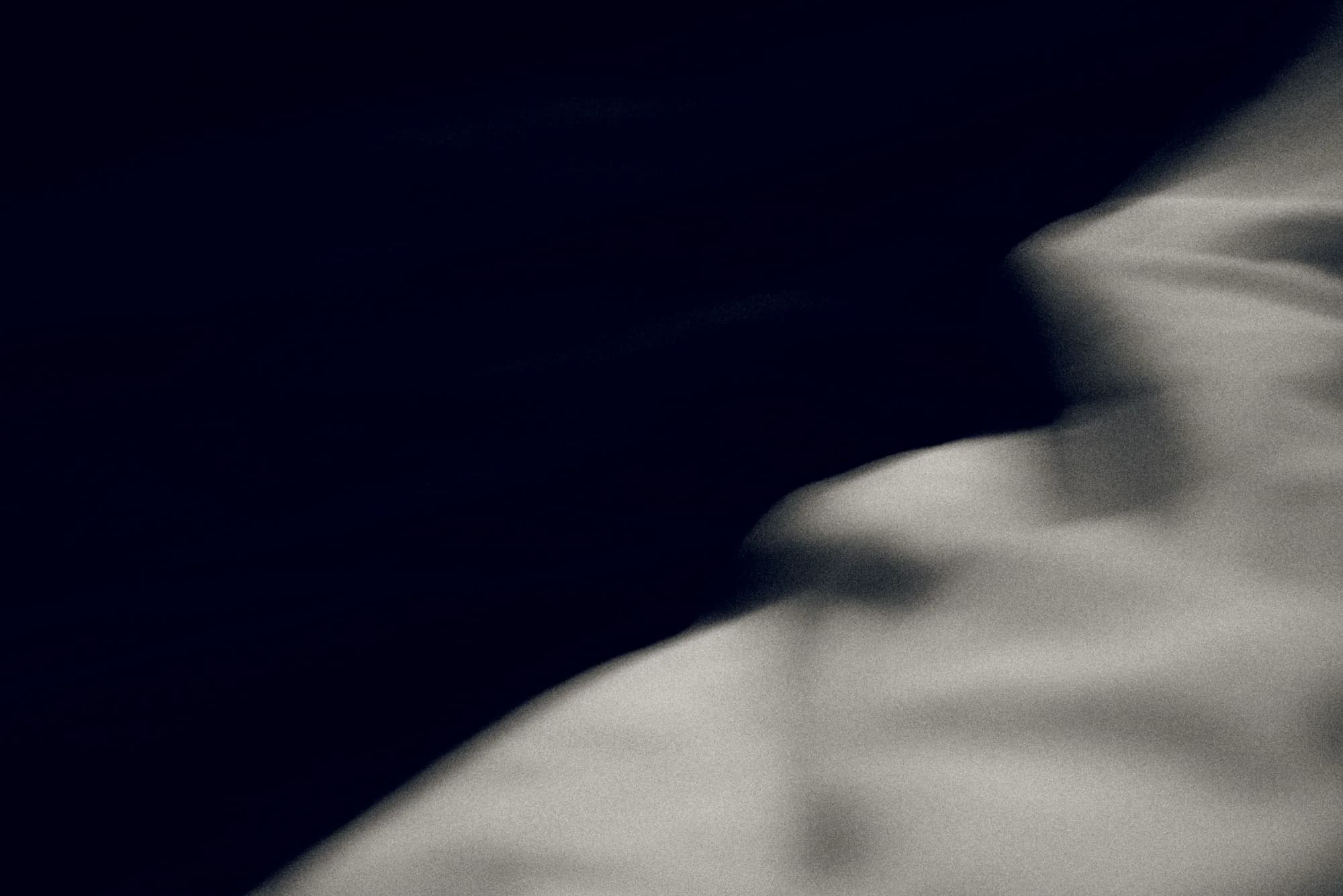A dark fold of fabric, out of focus.